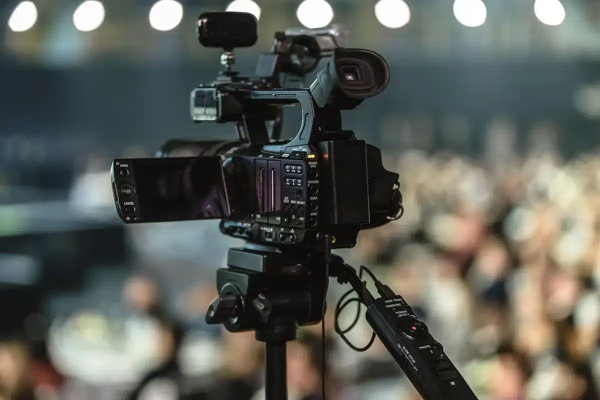 A row of television cameras left idle outside a government gate, lens covers on, tripod legs folded, an atmosphere of suspended coverage