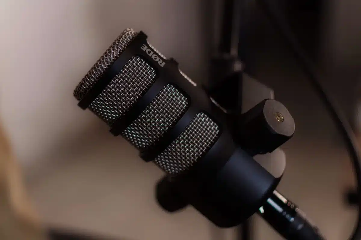 A lone, empty podcast microphone on a small table beside a laptop showing a generic subscription page; no logos or text, soft studio lighting