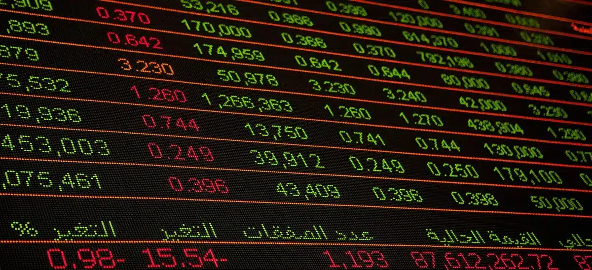 A stock market trading floor or financial data center with multiple screens displaying employment statistics, charts, and real-time market data in focus