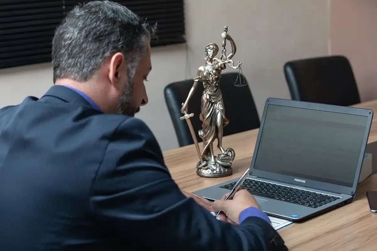 A small stack of legal files and a generic government ID badge resting on a wood table beside a closed notebook, an empty mug nearby to imply a staff departure