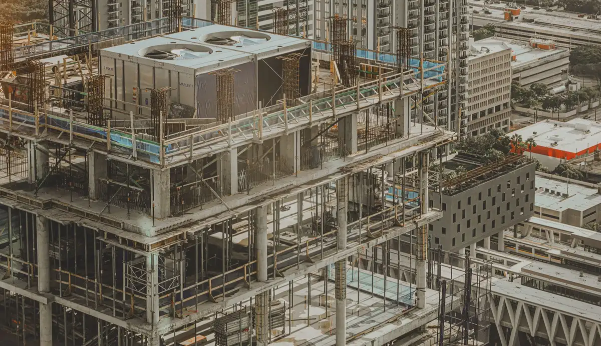 An empty modern construction site with a tall concrete core rising, cranes in the background and no workers visible, a street-level view toward the future tower