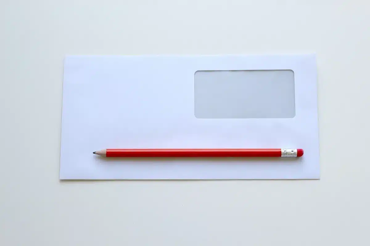 A stack of correspondence envelopes on a mahogany desk with a fountain pen nearby, a royal guard silhouette out of focus in background