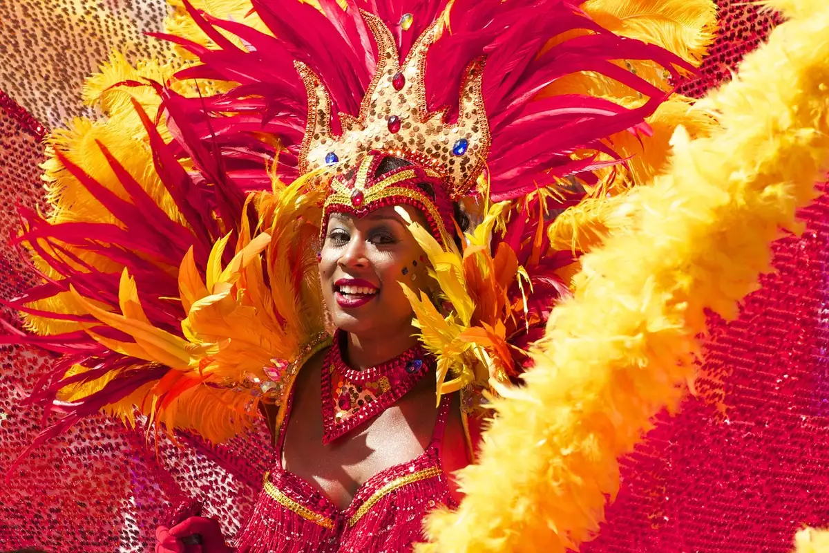 Festive parade scene with marching bands, colorful floats, and street banners on a sunny day, crowds lining both sides of a downtown street.