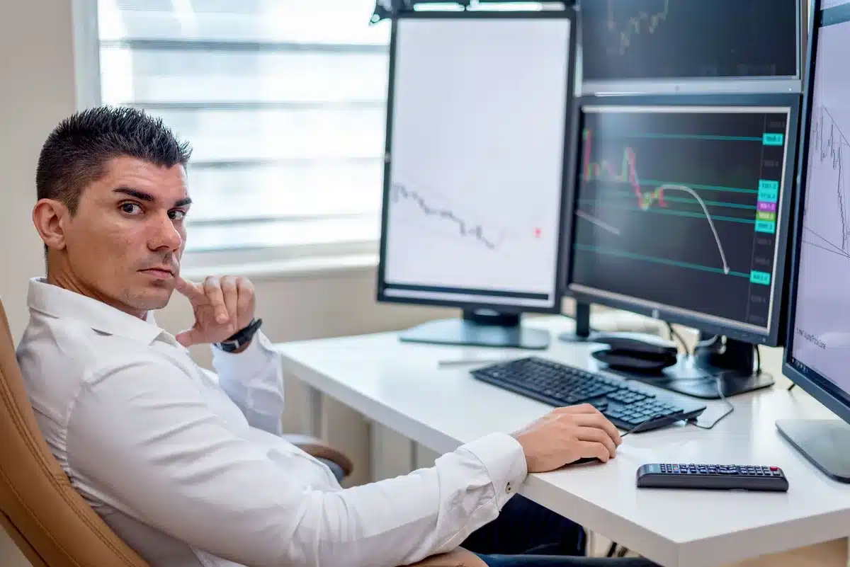 empty trading desk with a single chair and multiple anonymized monitors displaying charts; no logos or identifiable persons