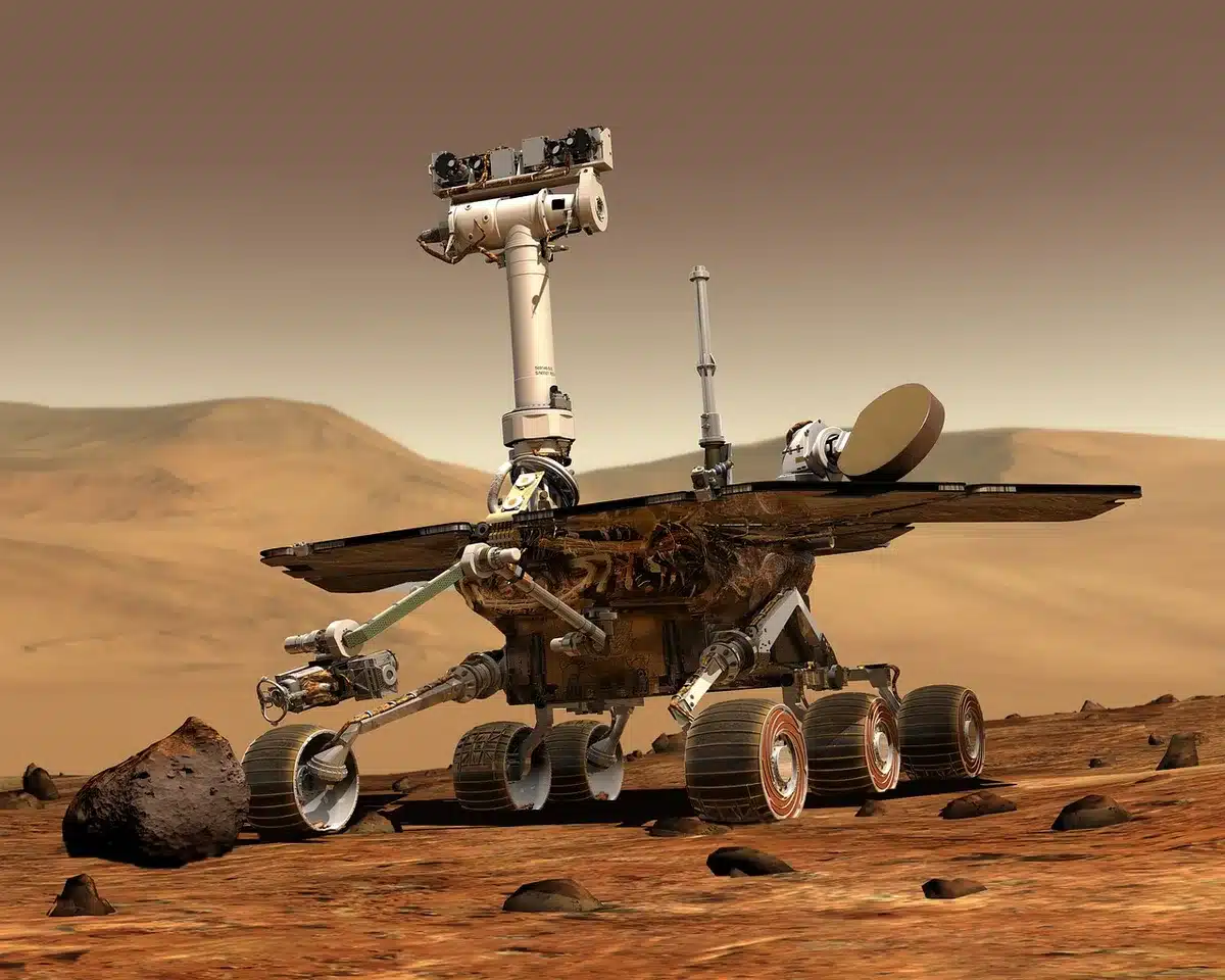 An anonymous dusty Martian surface scene showing several small sealed metal tubes arranged on the ground next to a shallow disturbed patch of regolith, no logos or people