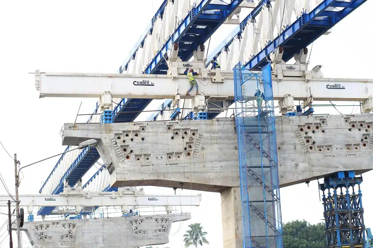 A diverse group of construction workers and tradespeople in safety gear collaborating on a job site, focused on hands-on work and mentorship moments, symbolizing partnership and workforce development.