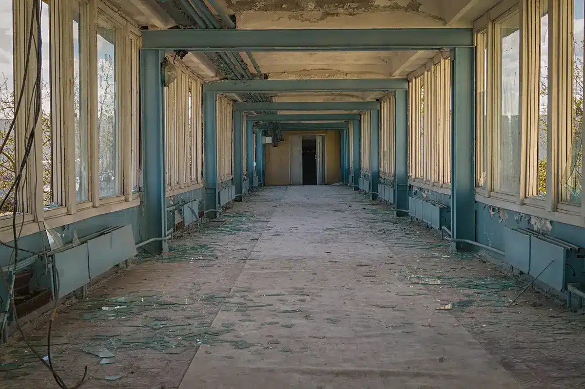 A dimly lit conference corridor outside a media interview room, with anonymous camera tripods and an open door at the far end