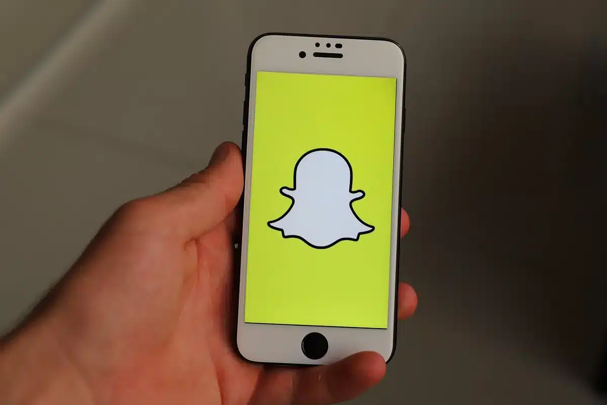 A smartphone screen displaying social media text post, the glow illuminating the edges against a dark background, the text blurred but readable as a statement, fingers hovering near the device.