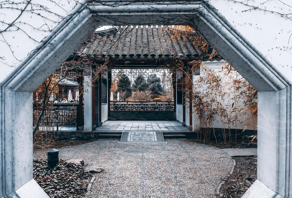 A private school's entrance gate in autumn, ivy-covered stone pillars, morning light catching on polished brass plaques, an empty courtyard beyond, the sense of institutional tradition and exclusivity, no children visible