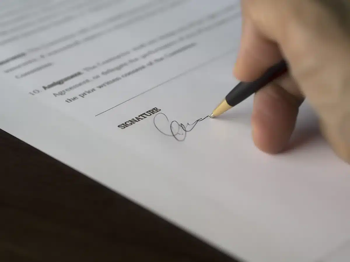 a close-up of anonymous hands holding a printed shareholder notice next to reading glasses on a table, a blurred calendar in the background showing late September
