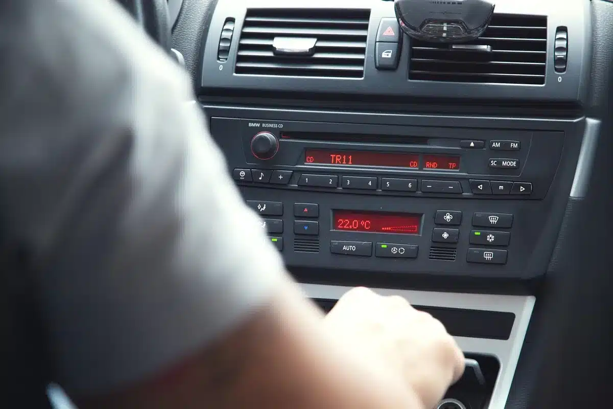 Two anonymous hands passing a folded paper labeled 'notes' (no visible text) across a radio console, a coiled microphone cable in the frame