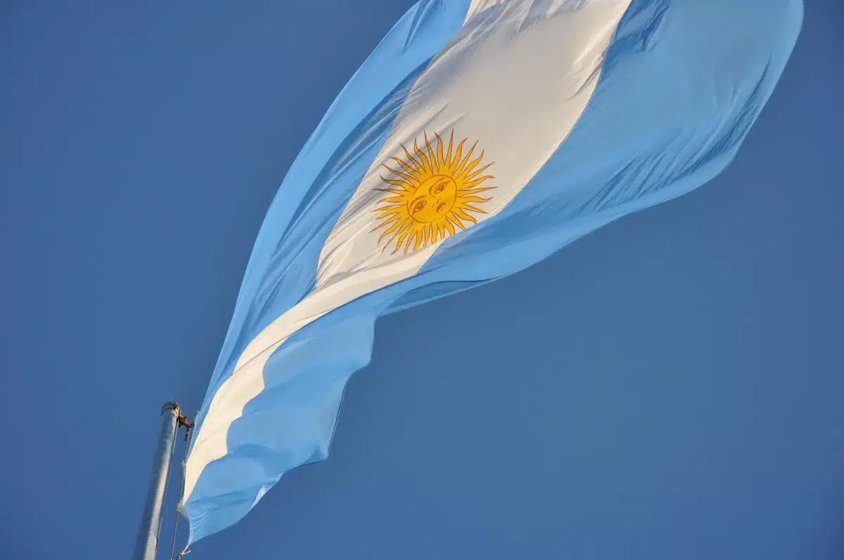 Flags of Argentina and Britain facing each other across a map of the South Atlantic, with the Falkland Islands marked between them, diplomatic tension conveyed through stark color contrast