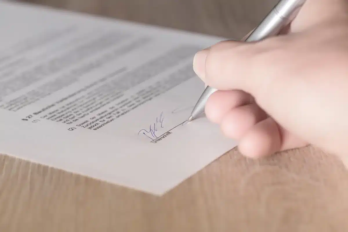 A close-up of a stack of signed petition sheets with anonymous hands in the background, hinting at citizen-driven referendum action