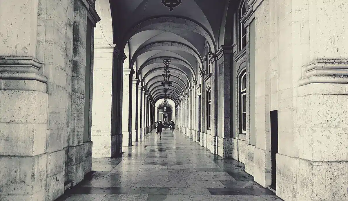 Closed courthouse corridor viewed from a distance, polished floor reflecting overhead lights and an empty folding table with papers on it