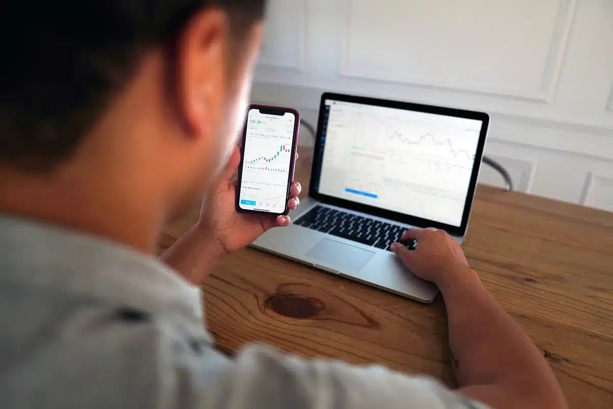 Crowded stock exchange trading floor with red and green price indicators flashing, traders monitoring screens showing Nike ticker symbol declining, market chaos and urgency visible in anonymous faces and body language.