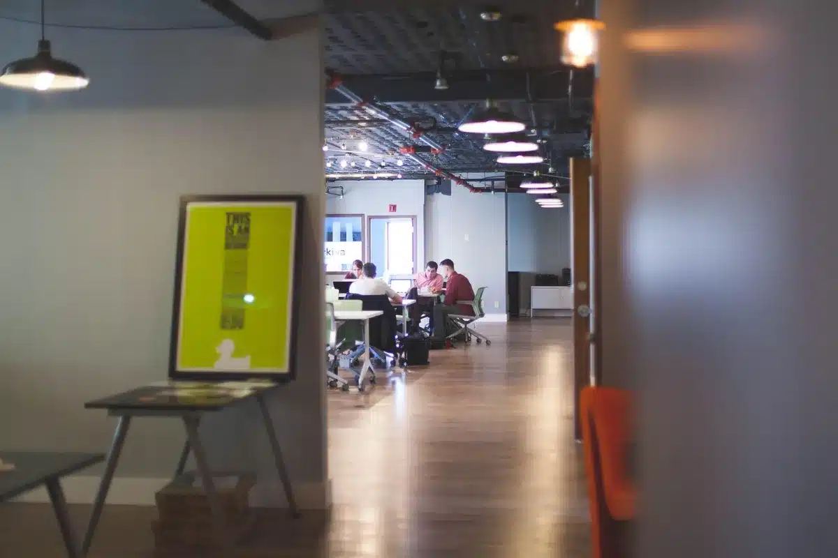 A conference table in a modern office setting with empty chairs around it, documents and pens arranged neatly, a large window showing a cityscape of industrial buildings and cranes, soft natural light, sense of negotiation and decision-making