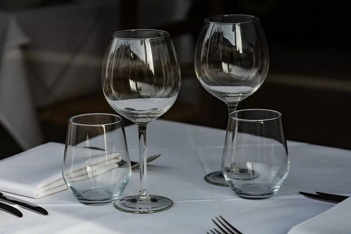 an empty formal dining table set for a state dinner, place settings aligned under chandelier light