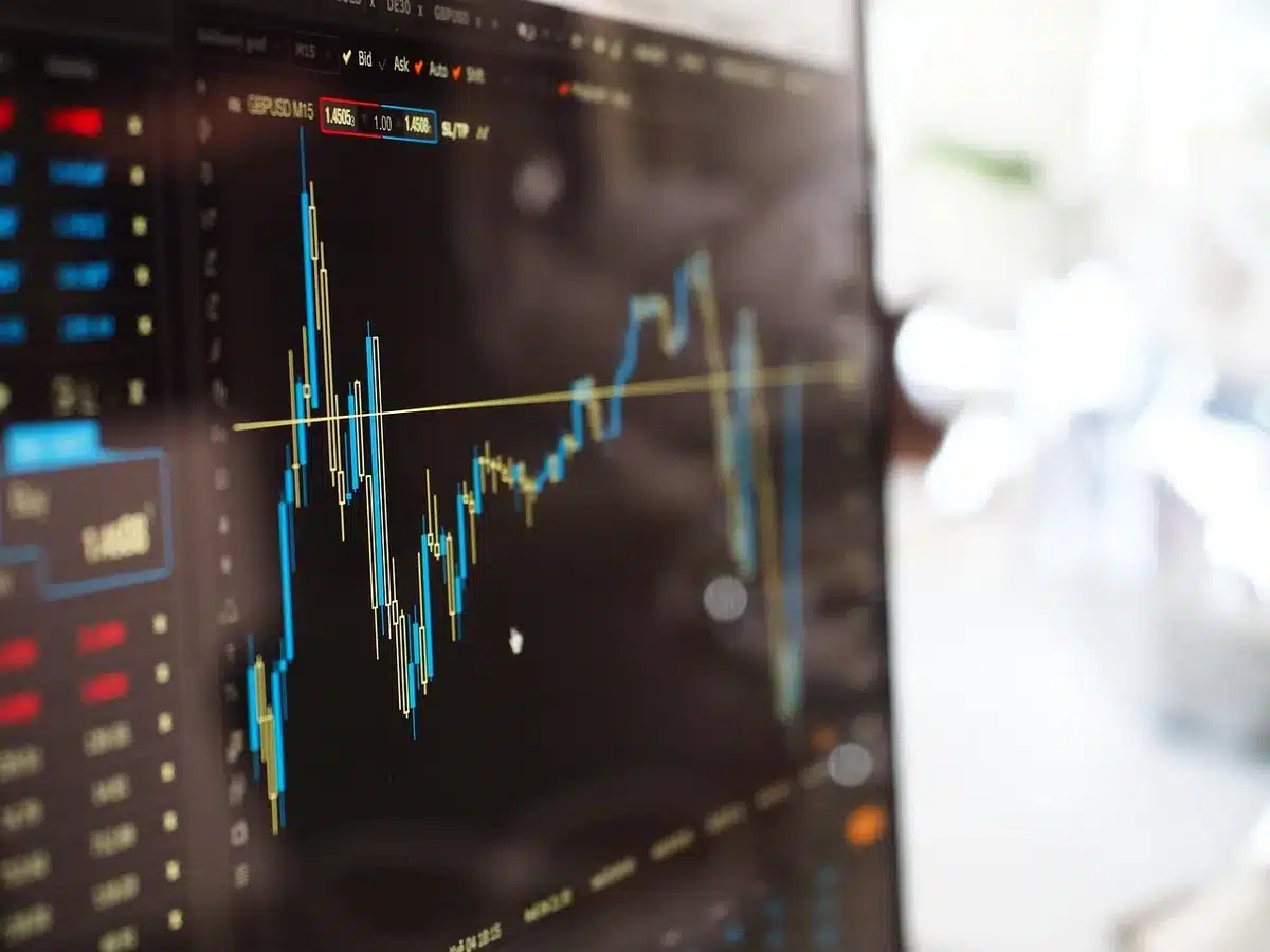 A stock market trading screen displaying red price charts and oil barrel symbols, reflecting market anxiety and financial volatility during geopolitical crisis.