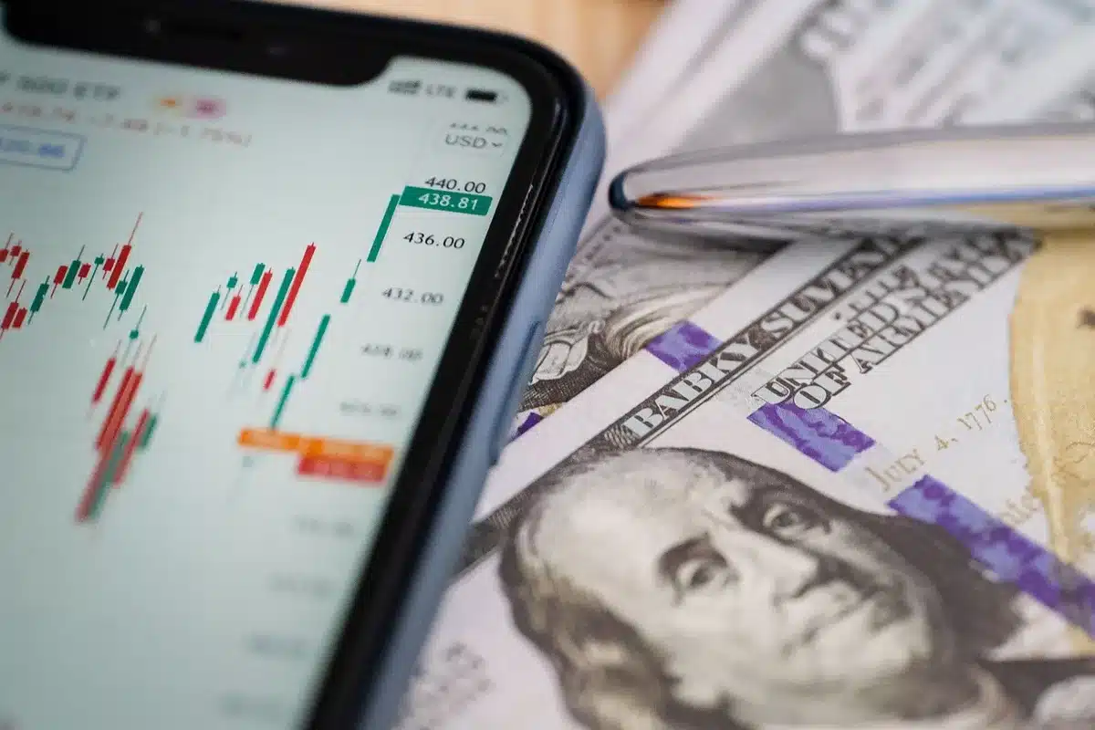 Close-up of an anonymous trader's hands over a laptop screen showing currency charts, screen content blurred and unbranded
