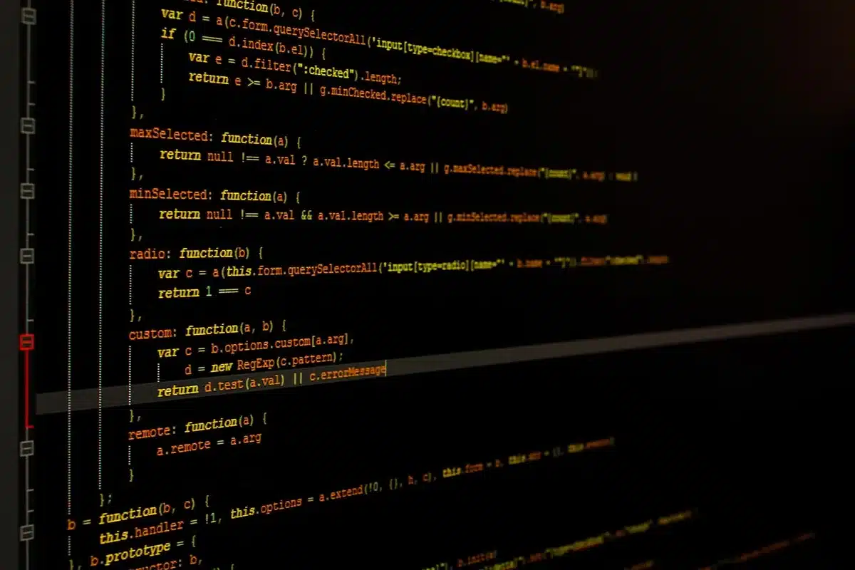 A developer's workspace with a smart ring beside a laptop screen displaying AI interface code, suggesting software development for wearable devices.