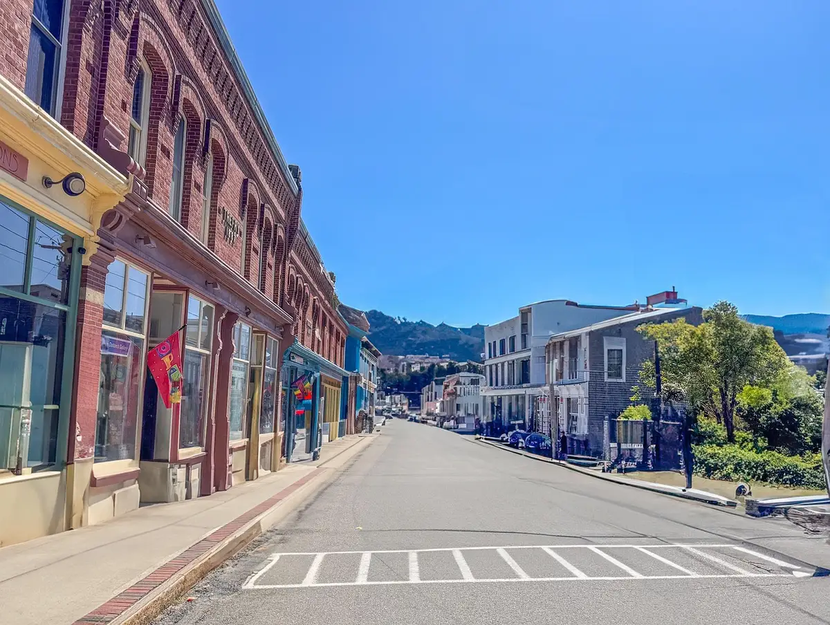 A small-town Main Street with an American flag on a lamppost and an empty storefront window, a campaign-style flyer pinned to a bulletin board blurred in the foreground — evokes local town halls and retail politics