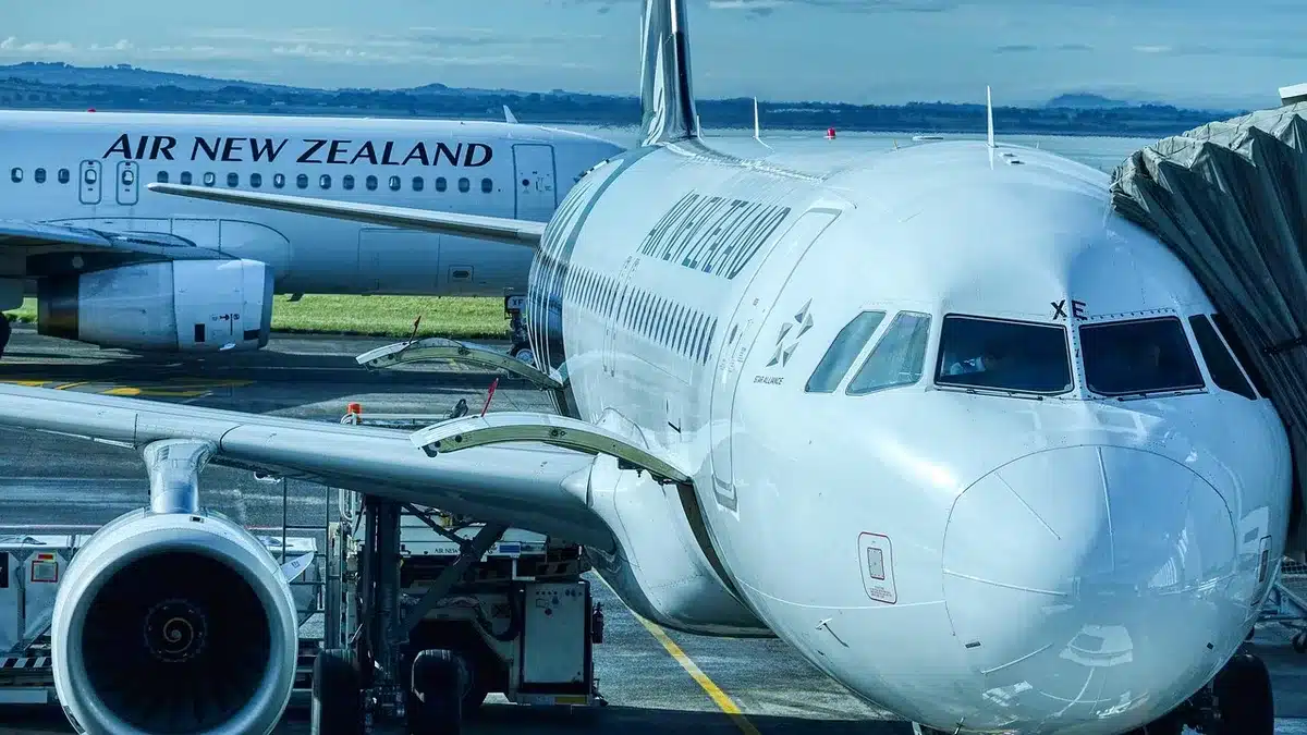 A sleek black autonomous aircraft with fixed landing gear on an airport tarmac, 80 feet long with a distinctive streamlined fuselage, dwarfing nearby ground equipment and hangar structures in morning light.