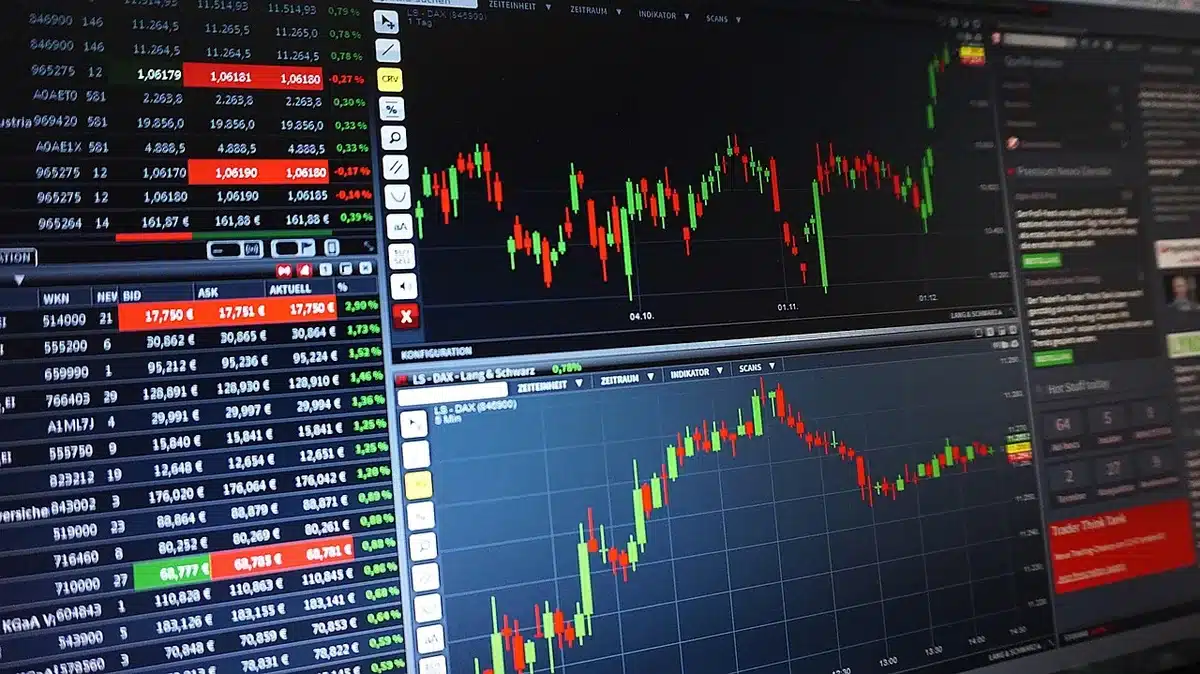 A busy trading desk with multiple financial professionals monitoring screens showing stock indices and economic indicators, papers with data scattered across desks, the energy of real-time financial analysis
