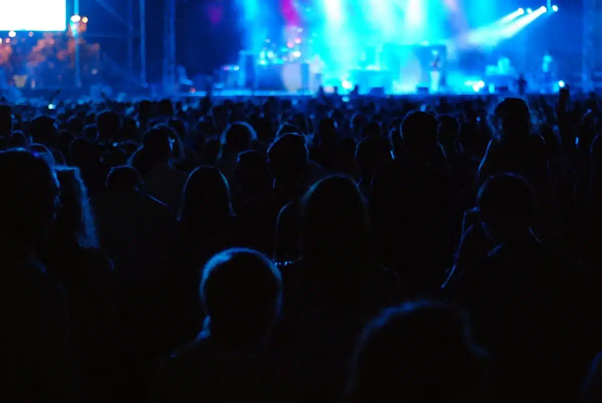 A distant, anonymous crowd in a festival-style outdoor ballpark celebrating under string lights, no visible logos, people as blurred silhouettes — triumph
