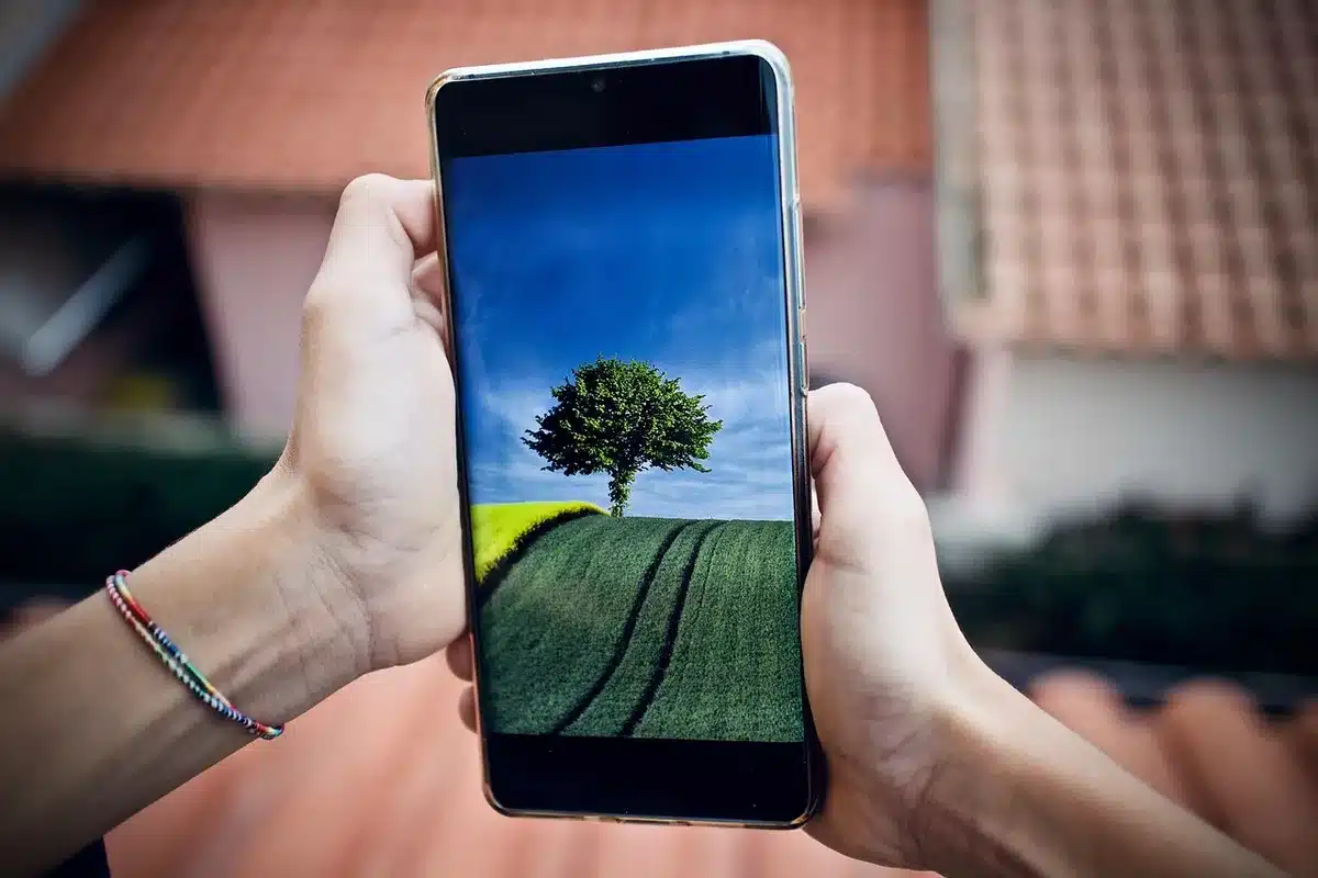 Close-up of an anonymous smartphone screen showing a blurred social feed and a finger hovering over the comments, no profile images or text visible