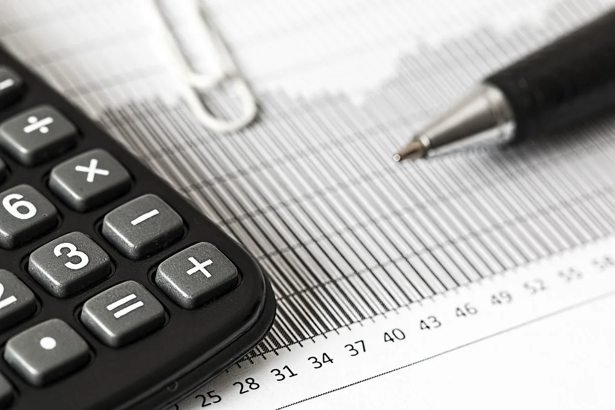 A retiree reviewing financial documents showing benefit statements and calculator on a home desk, morning light streaming through a window, warm and contemplative mood