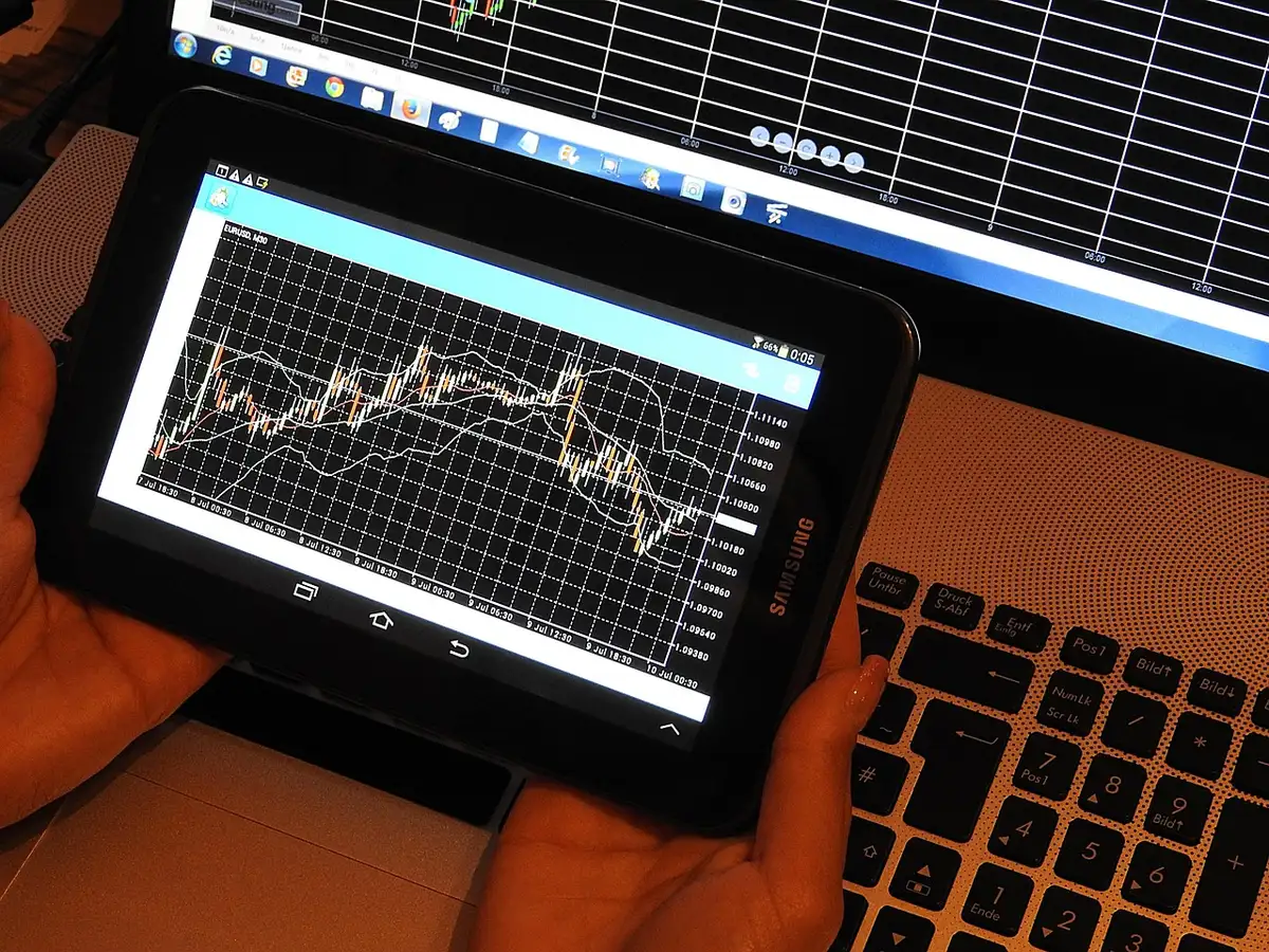 a close-up of an anonymous person's hands holding a generic monthly inflation chart printout on a dining table, cup of tea beside it