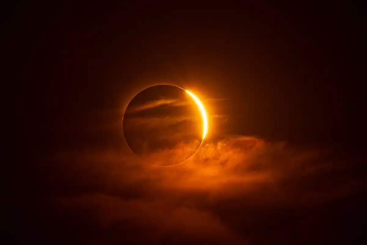 Solar flare eruption visible on the sun's surface, bright magnetic loops and plasma arcs against the dark corona, intense orange and white light