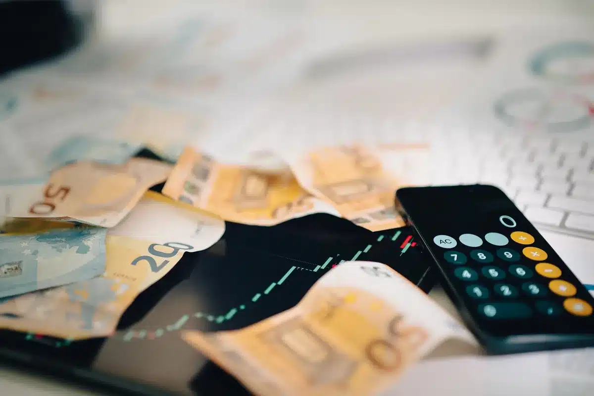 An anonymous trader's hands on a keyboard with a large unbranded wall screen showing an index chart in the background; no logos visible