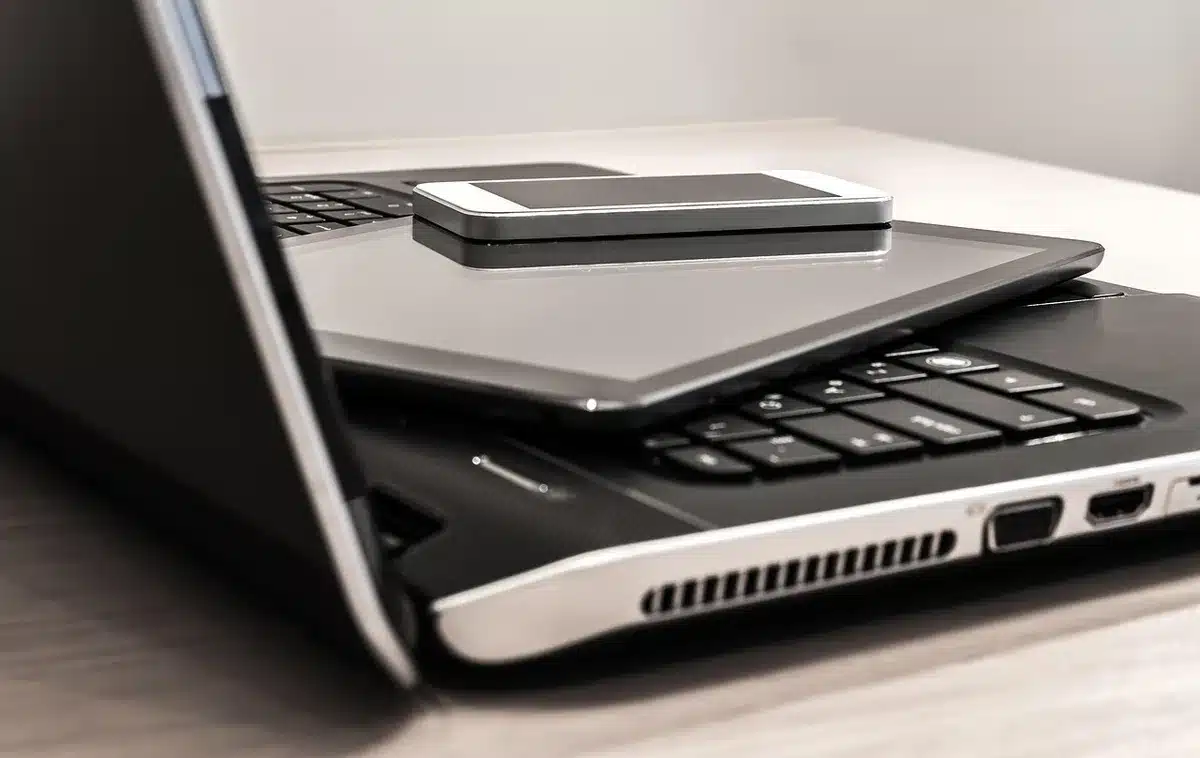 dimly lit studio table with an anonymous black circular device and a slim touch-screen tablet side by side