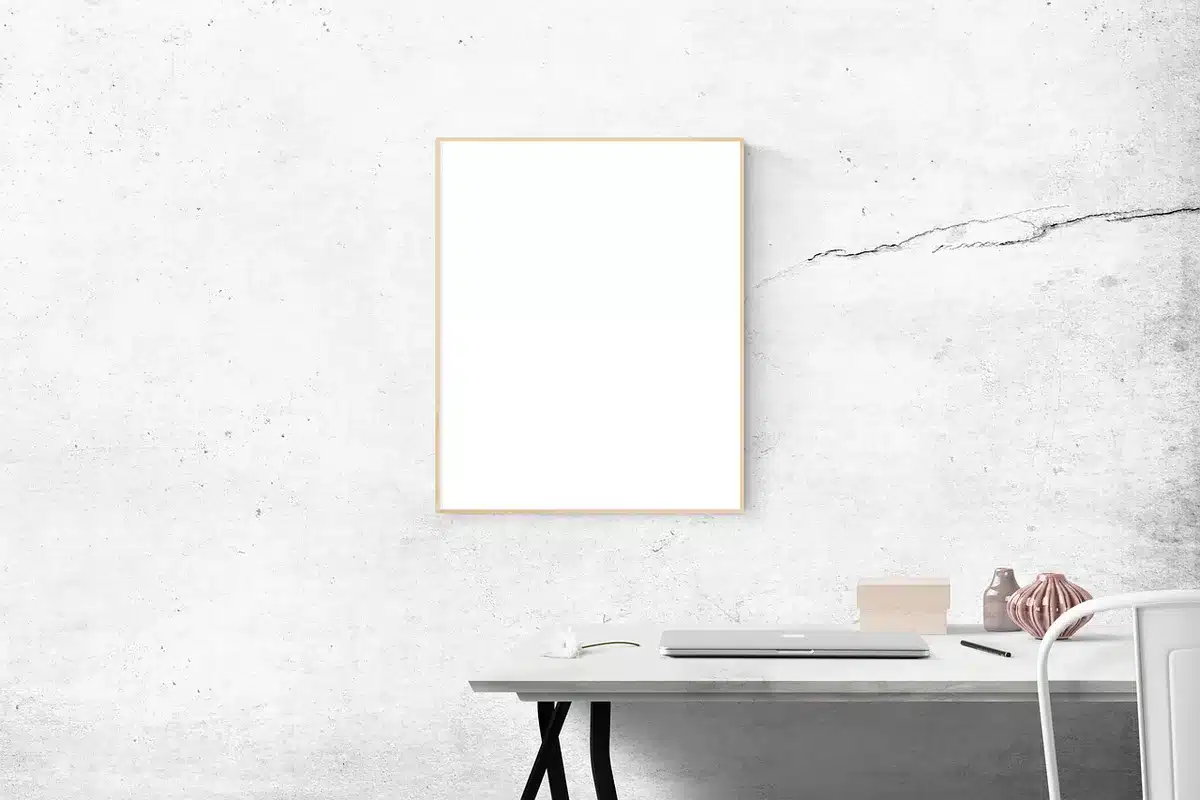 Empty design studio with minimalist workstations, soft natural light through large windows, a single prototype device on a central table awaiting critique
