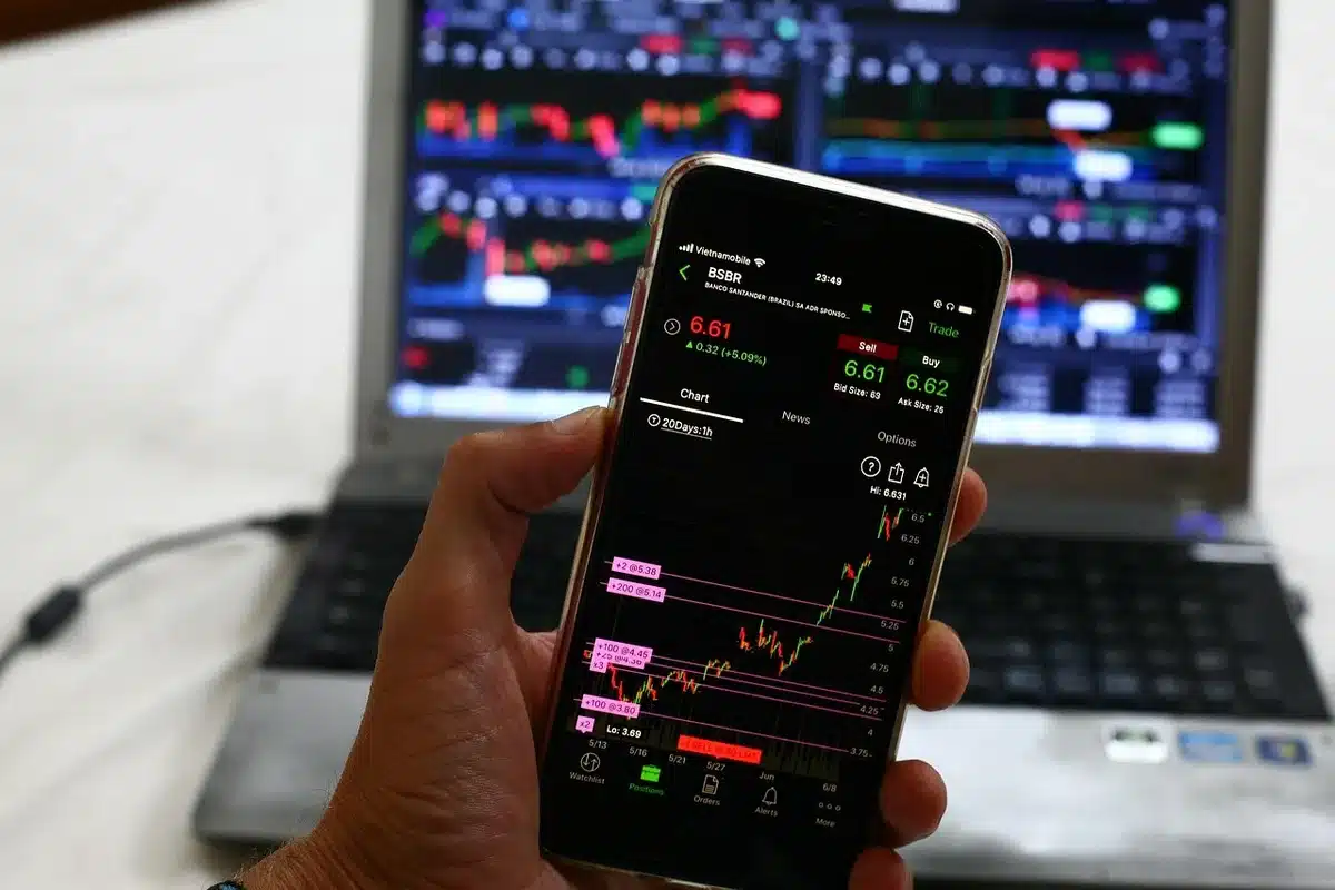 a close-up of hands typing on a laptop with a financial chart visible on screen, anonymous workspace scene