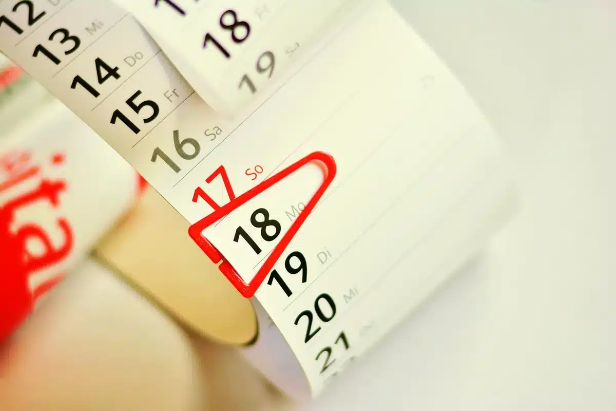 a blank earnings calendar page on a desk with a pen and anonymous hands nearby, no brand names, indicating planning for a busy reporting week