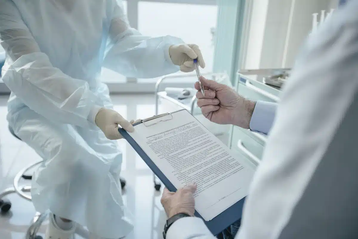 A small anonymous stack of medical folders and a generic patient chart on a table, a pen resting on top; no names or logos visible