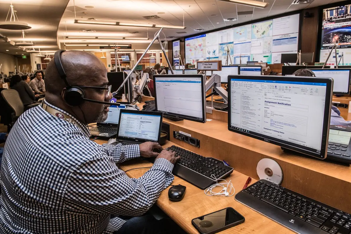 anonymous silhouette of a person looking at multiple headline tiles on a large newsroom screen, faces blurred and indistinct