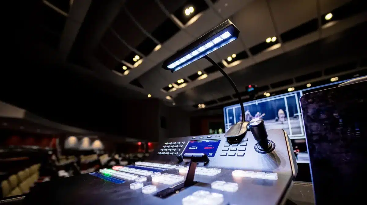 Anonymous silhouette of a person at a broadcast control desk watching multiple screens showing news feeds, face unseen