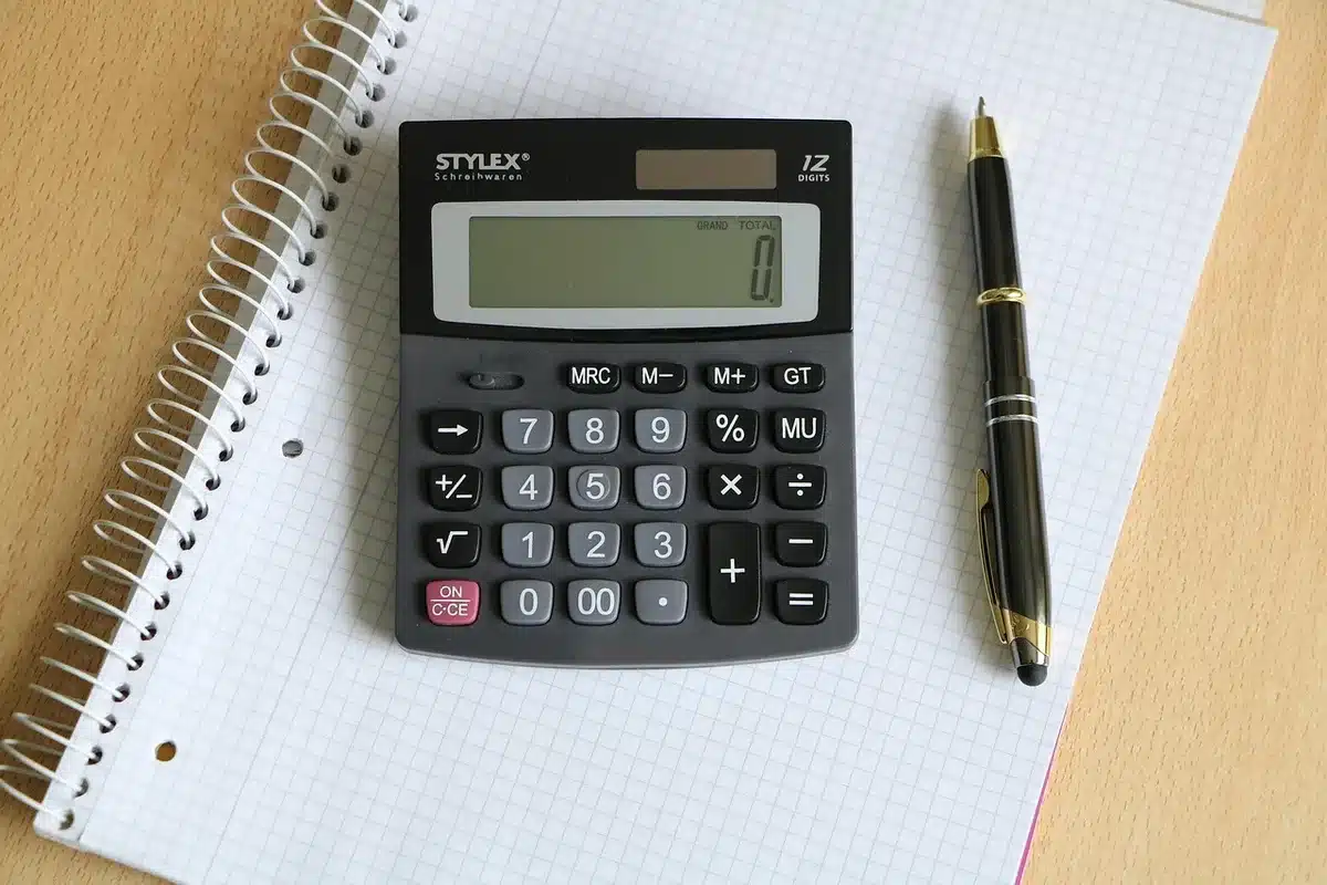 Empty mortgage application form on a desk with a calculator showing rising numbers, documents stacked nearby, dim lighting suggesting financial stress