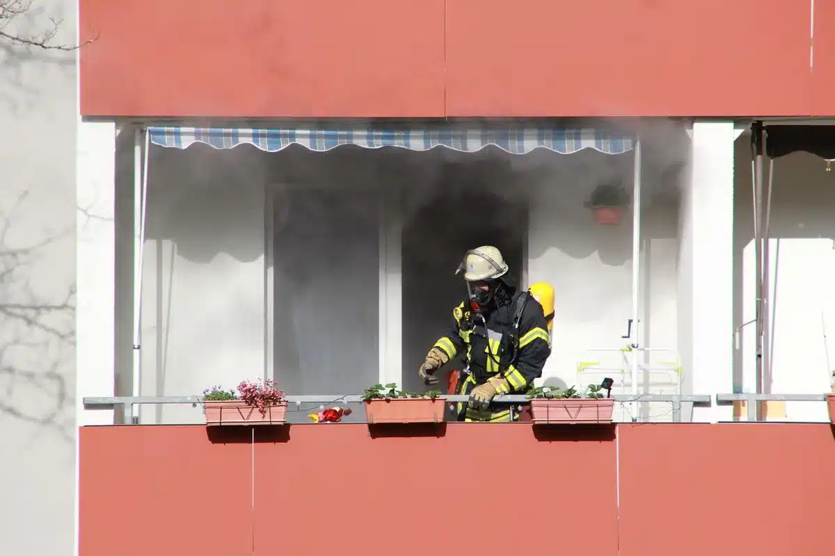 A close-up of a worn firefighter's helmet resting on a piece of twisted metal wreckage, with dust particles visible in soft light
