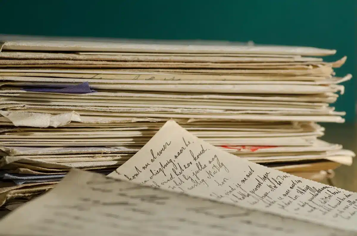 An anonymous stack of printed refund letters and plain envelopes on a kitchen table, a pen and a generic check peeking from one envelope, no names or logos visible
