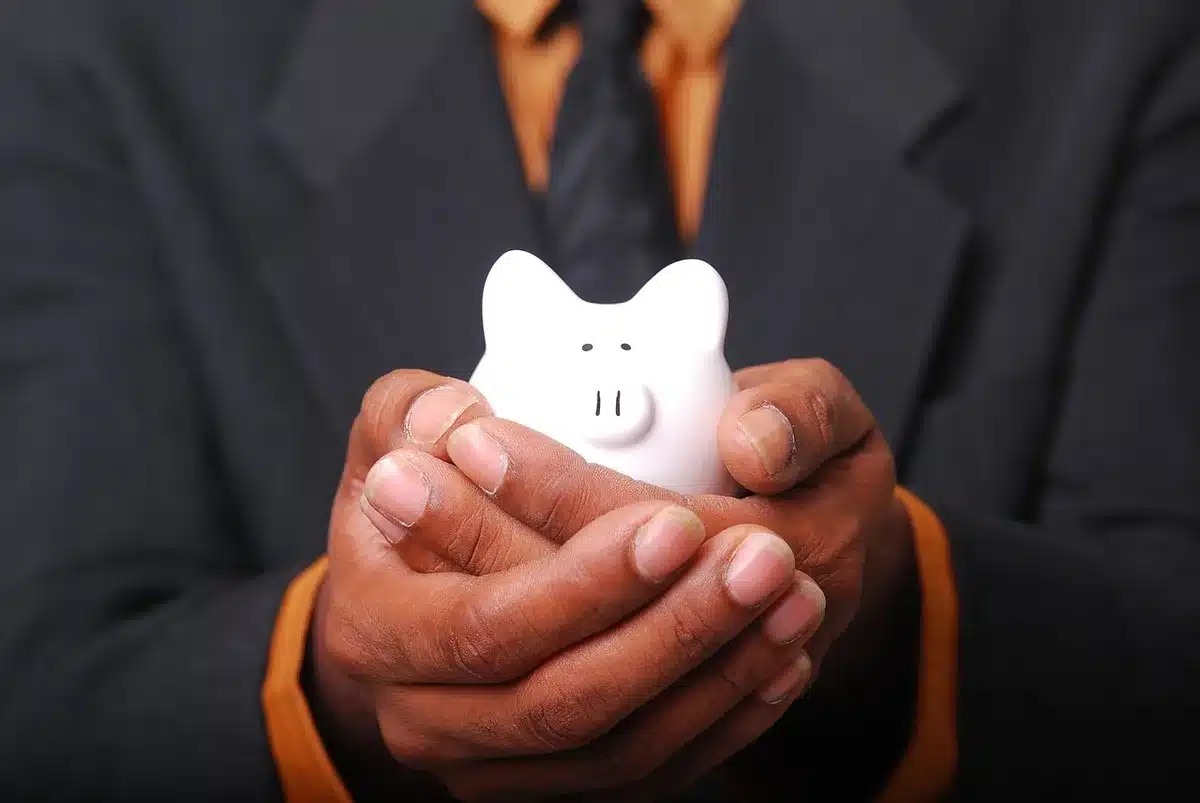 Empty child-sized piggy bank on a small wooden table, single coin beside it, soft daylight through a nearby window