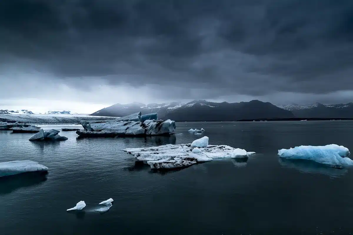 An empty Arctic coastal outpost at dusk, a generic concrete cold-weather shelter and communications mast against a pale sky, no signage or flags