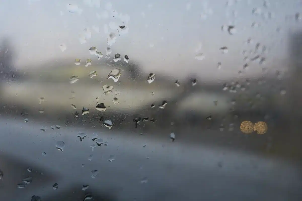 A worn poster leaning against an airplane window, lettered headline blurred but readable as a demolition concept, a silhouetted hand pointing toward it