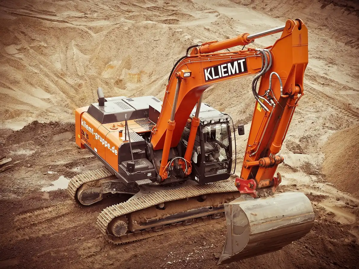 An empty construction site with massive structural frameworks and steel beams rising from an excavated foundation, dust suspended in afternoon light, heavy machinery idle at the perimeter, a gaping hole where historic architecture once stood