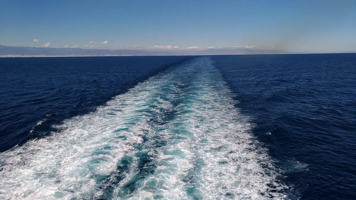 Cargo ship in dim light navigating a narrow waterway, tension visible in the scene