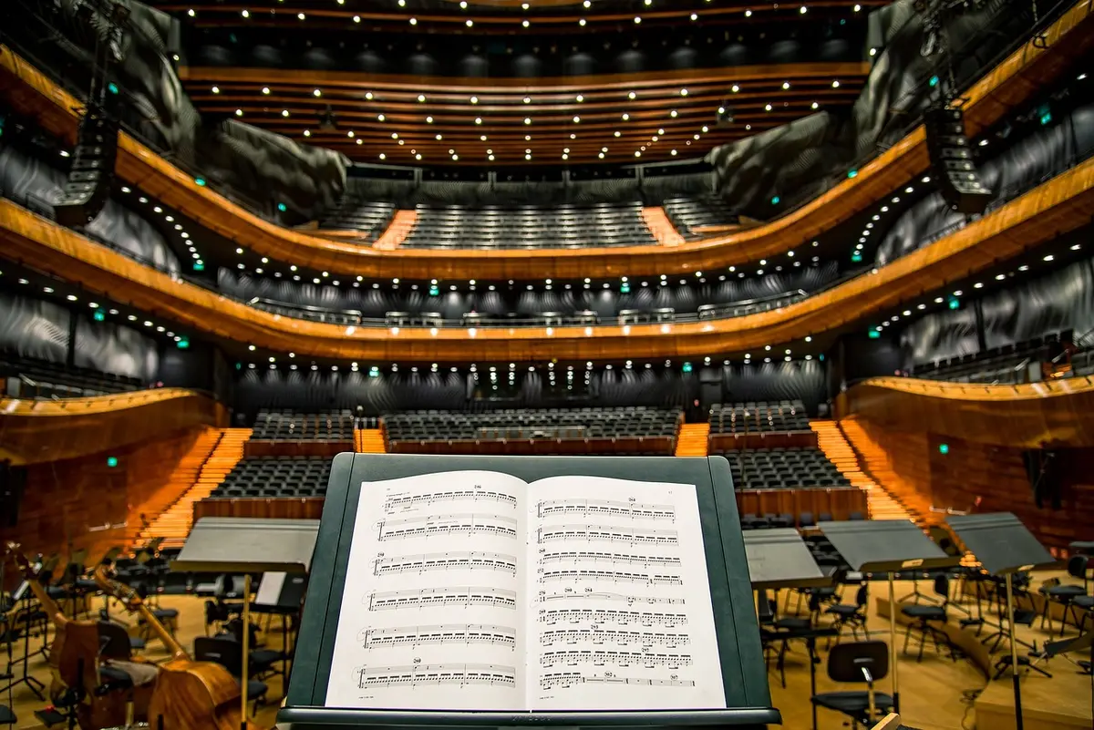 A wide-angle view of an empty corporate auditorium with a single microphone on a stand and rows of unbranded chairs, implying a major internal announcement
