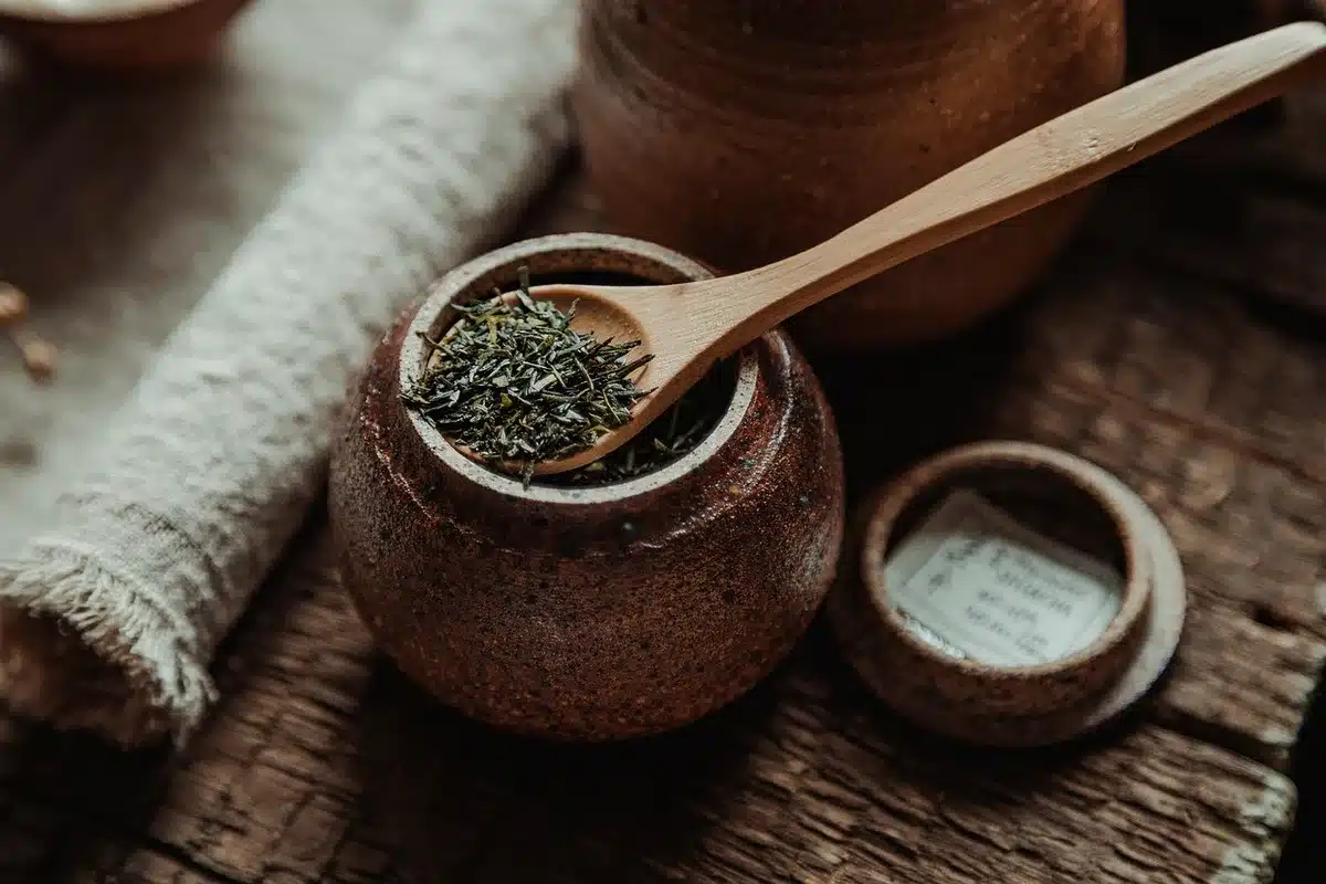 Close-up of three small tasting spoons on a counter next to a printed ingredient list and a tablet screen showing a text prompt; no logos or people